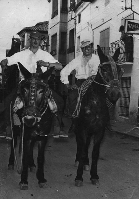 Dos hombres sobre dos burros en una calle de Calamocha.